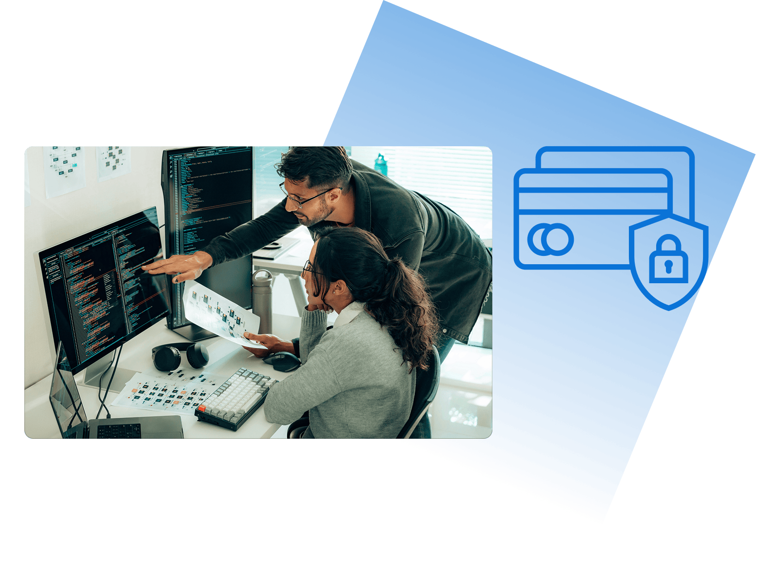 Colleagues collaborate on coding at a dual-monitor setup, pointing at code with printed documents on a desk.